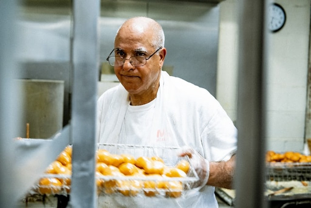 Padeiro manuseando recipiente com pães, representando equipamentos para padaria