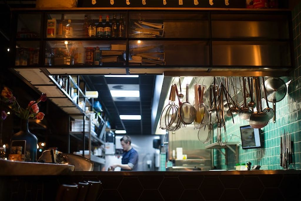 Cozinha de restaurante com equipamentos para restaurante e funcionário sorrindo