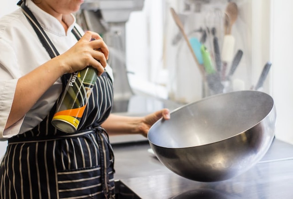 Profissional segurando um equipamento de cozinha industrial, uma espécie de tigela bowl de inox