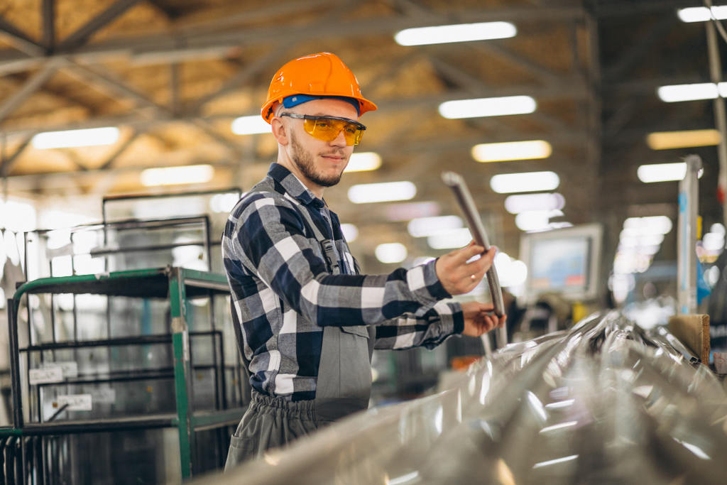 Profissional com capacete e óculos de prodeção segurando pedaço de aço inoxidável